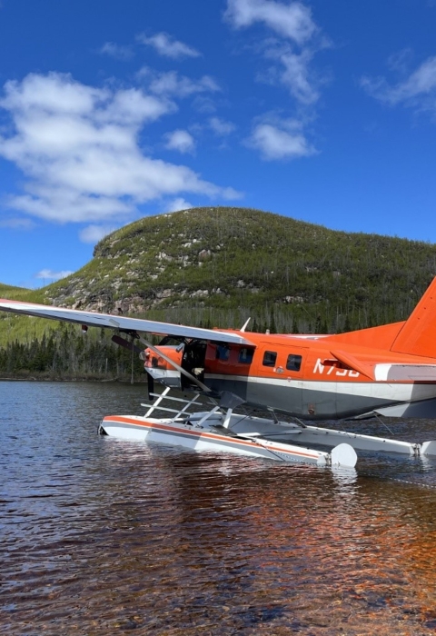 airplane floating on water with mountains in the background