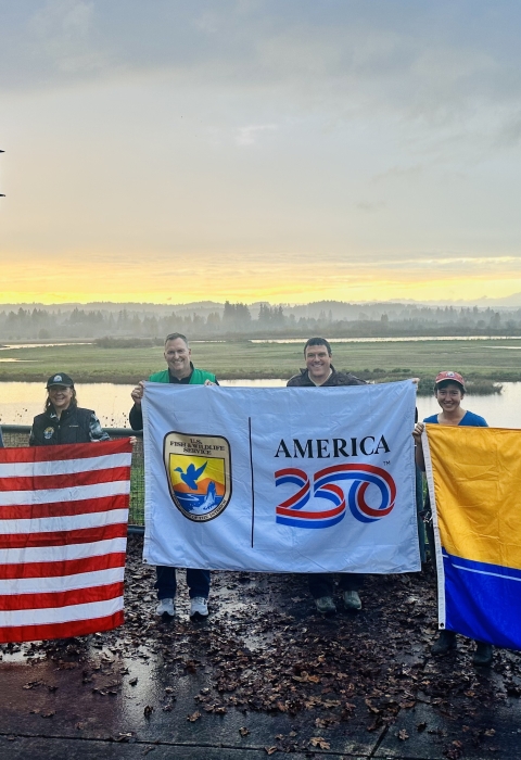 8 people in front of wetland holding 3 flags, Betsy Ross US flag at left