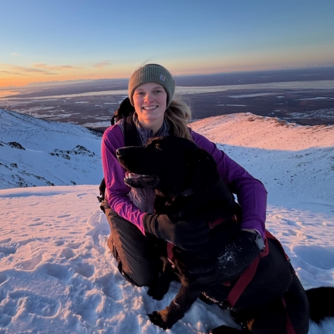 A picture of a woman on a snowy mountain with a dog