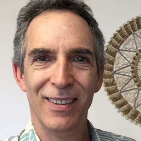 A man smiles into the camera with a Hawaiian shirt on