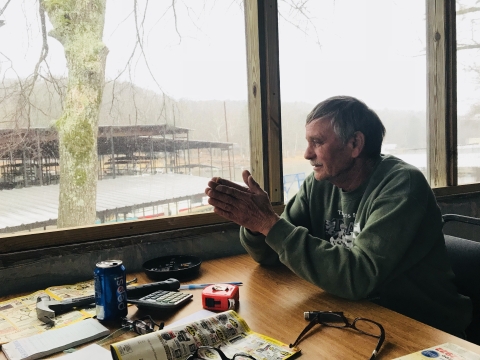 A man looking out the window at the marina he manages