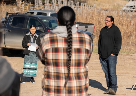 Three people are seen standing in a circle for a Tribal ceremony