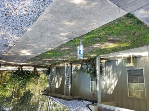 Gray office building with sidewalk in front of building and handicap sign.