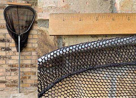 black net on a pole against a brick wall showing the net is wider than the 15 inch ruler propped up horizontally above the net's rim..