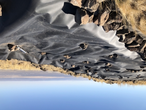 A water guzzler sits high on a ridge with a valley visible in the distant background.