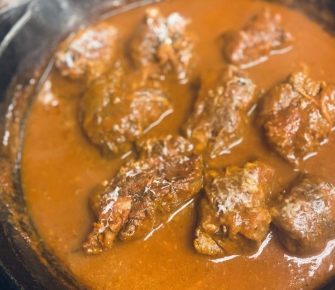 Pieces of meat for elk braciole braising in red sauce