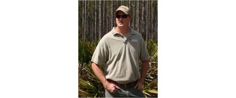 Seth Thompson, manager of Alapaha WMA, poses in front of a forest.