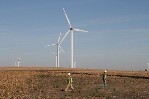 People searching a plot around a wind turbine with wind turbines in the background.