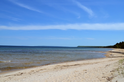 Calm water washes up on sandy beach.