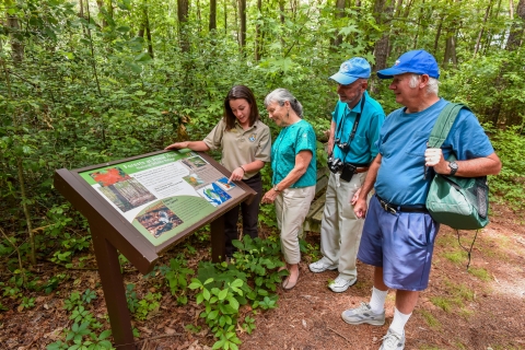 FWS Visitor services staffer shows interpretive panel to visitors