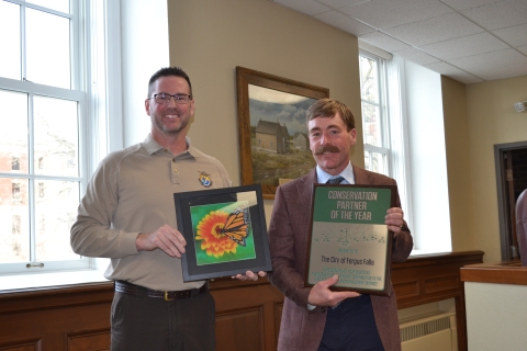 Two adults holding a plaque and a framed print