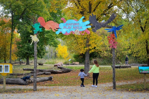 Parent and child walk into nature play area