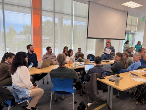 several adults gather around a table in conversation