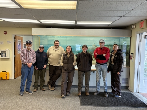 seven people stand together in an office building