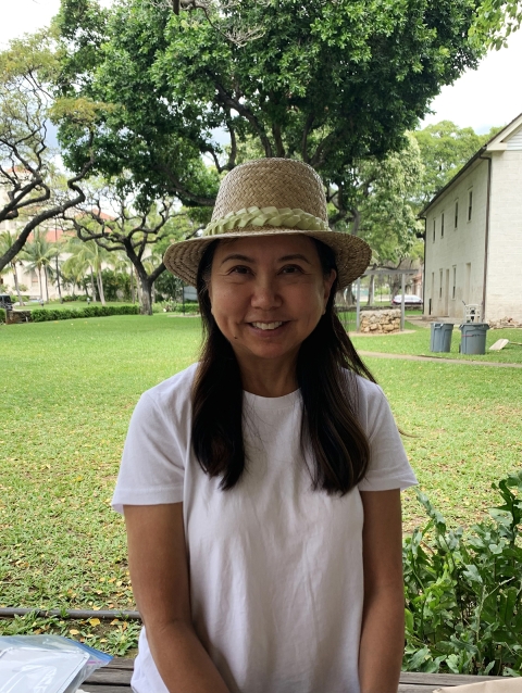 Susan Machida stands at the Mission Houses in Honolulu. She is wearing her first completed lauhala pāpale.