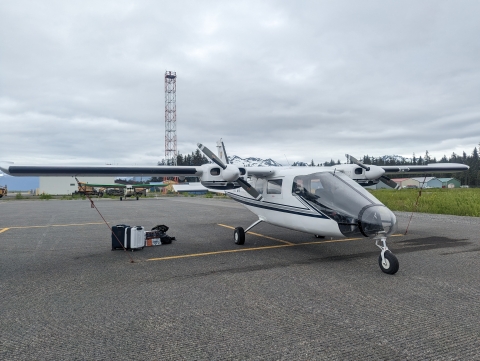 A Partenavia aircraft parked and tied down to concrete with gear waiting to be packed beneath the wing.