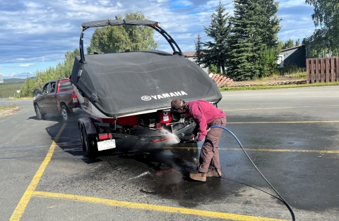 Watercraft inspector performs hot-wash to decontaminate a boat from potential aquatic invasive species. 