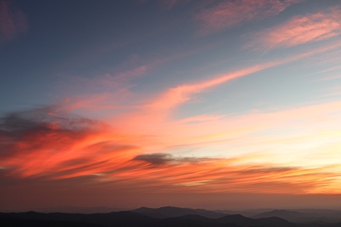 Clouds reflecting the setting sunlight over rolling mountains
