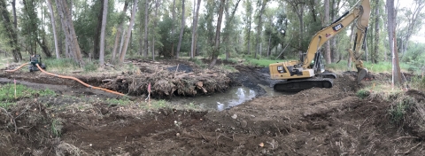 Image of construction taking place on a river side channel with a bulldozer