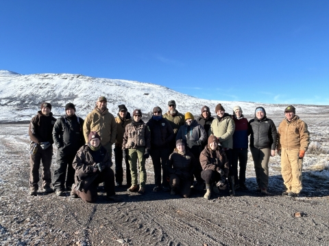 Sixteen team members are standing for group photo in snowy backdrop of Hart Mountain National Antelope Refuge.