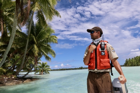 Stefan Kropidlowski operates a boat at Palmyra Atoll looking at palm trees to his right