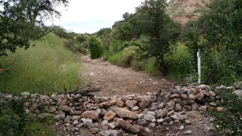 A pile of rocks lined up on one end of a dry ephemeral wash