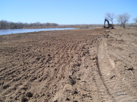 The bank by a body of water with a piece of construction equipment