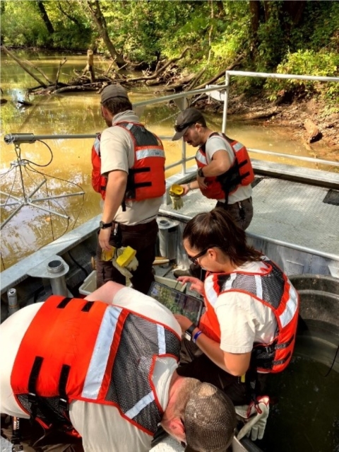 Image of 4 people in life vests working on a boat.