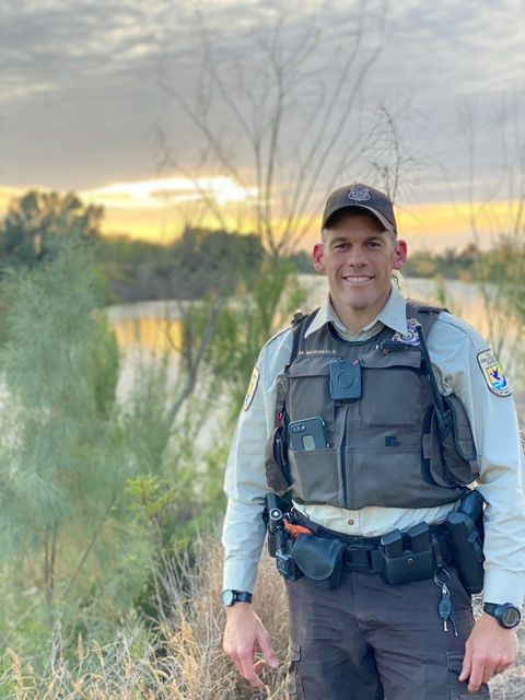a uniformed officer poses for a picture at the edge of a Southern Texas landscape 