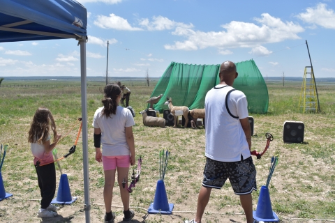 Two children and an adult set up for target practice with practice bows and practice targets.