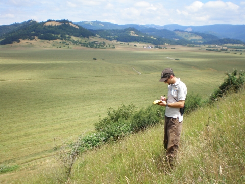 USFWS staff taking notes surrounded by hillsides and field