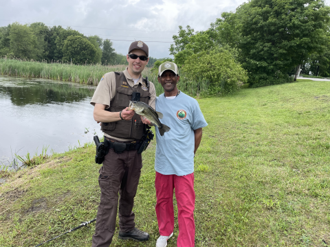A veteran poses with the bass he caught and Law Enforcement Officer Mike McMenamin at the annual Veterans' Fishing Derby at Wallkill River National Wildlife Refuge