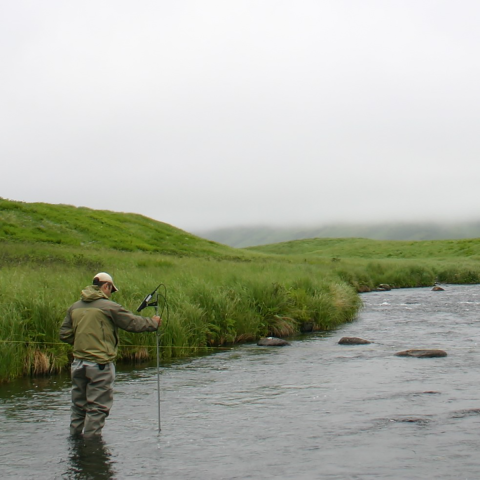 Looking up a stream with a hydrographer holding a wading rod making a streamflow measurement.