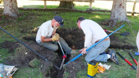 Two volunteers work on pipes