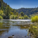 a landscape of a river with tree covered hills in the background