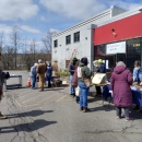 Community members standing in front of building collecting seeds.