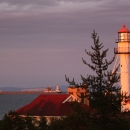 The lighthouse at Whitefish Point in Michigan with a freighter on Lake Superior and Canada in the background. 