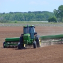 Tractor planting seed in plowed field