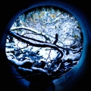 looking out at a snowy stream from within a round metal culvert pipe.