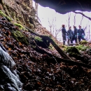 A group of four biologists wearing coveralls and helmets stand just outside the entrance to a mine