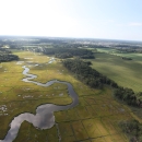 Green marshland, a wandering river and human-made canals are visible in this aerial of Cape May National Wildlife Refuge.