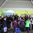 A large group of people standing under a pavilion smiling. A tent is seen in the background with the words "Elizabeth NJ Partnership" printed on the front
