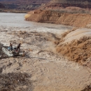 Image of 2 researchers on a raft near a muddy waterfall