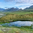 Green plains and a lake with a mountain range in the background.
