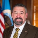 smiling man in front of US flag