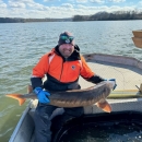 Man sitting in boat holding a fish. 