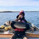 Woman sits on boat and holds big fish