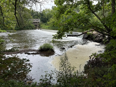 A view of a dam and river surrounded by trees.