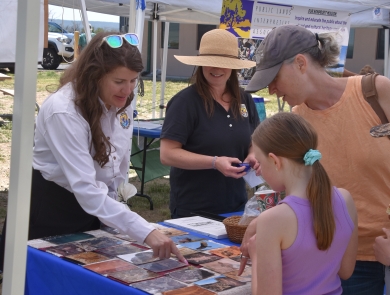 Two adults in FWS uniform show photographs to visitors.