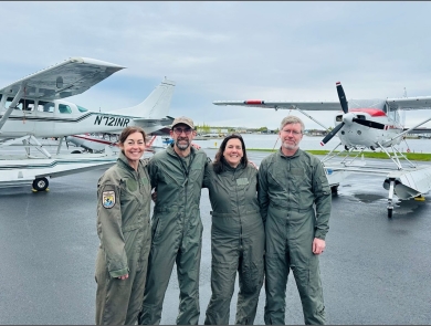four people standing in front of airplans